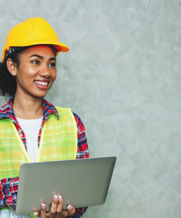 Portrait of professional young black woman civil engineer , architecture worker wearing hard hat safety for working in construction site or warehouse,using laptop for work.